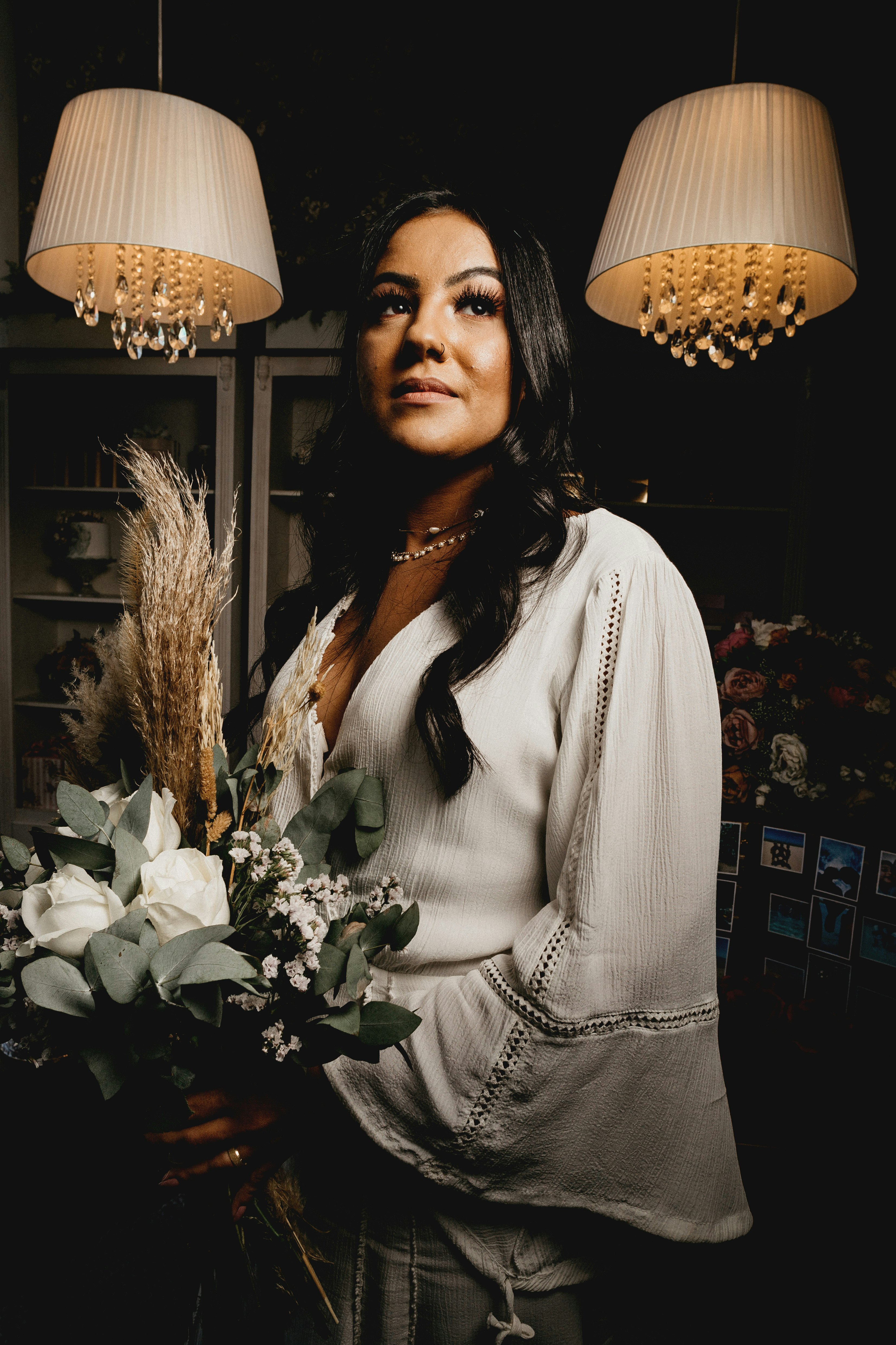 woman in white long sleeve shirt standing beside white flowers